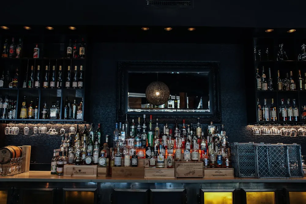 Dark wooden bar with backlit bottles and spirits