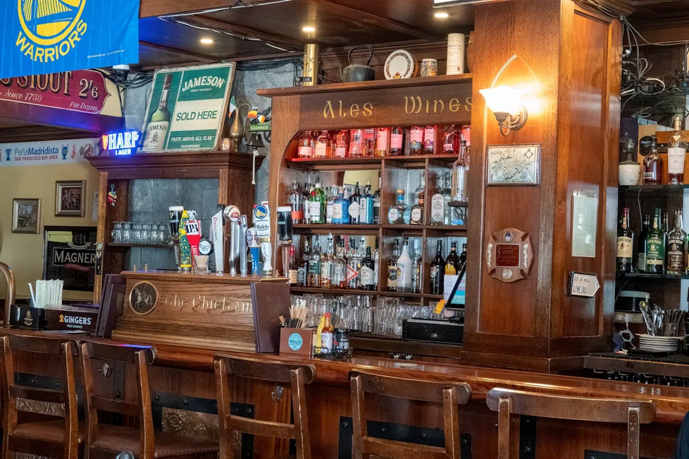 The warm interior of The Rambling House - dark wood bar counter with brass taps, warm amber lighting, and a welcome that hasn't changed in two centuries